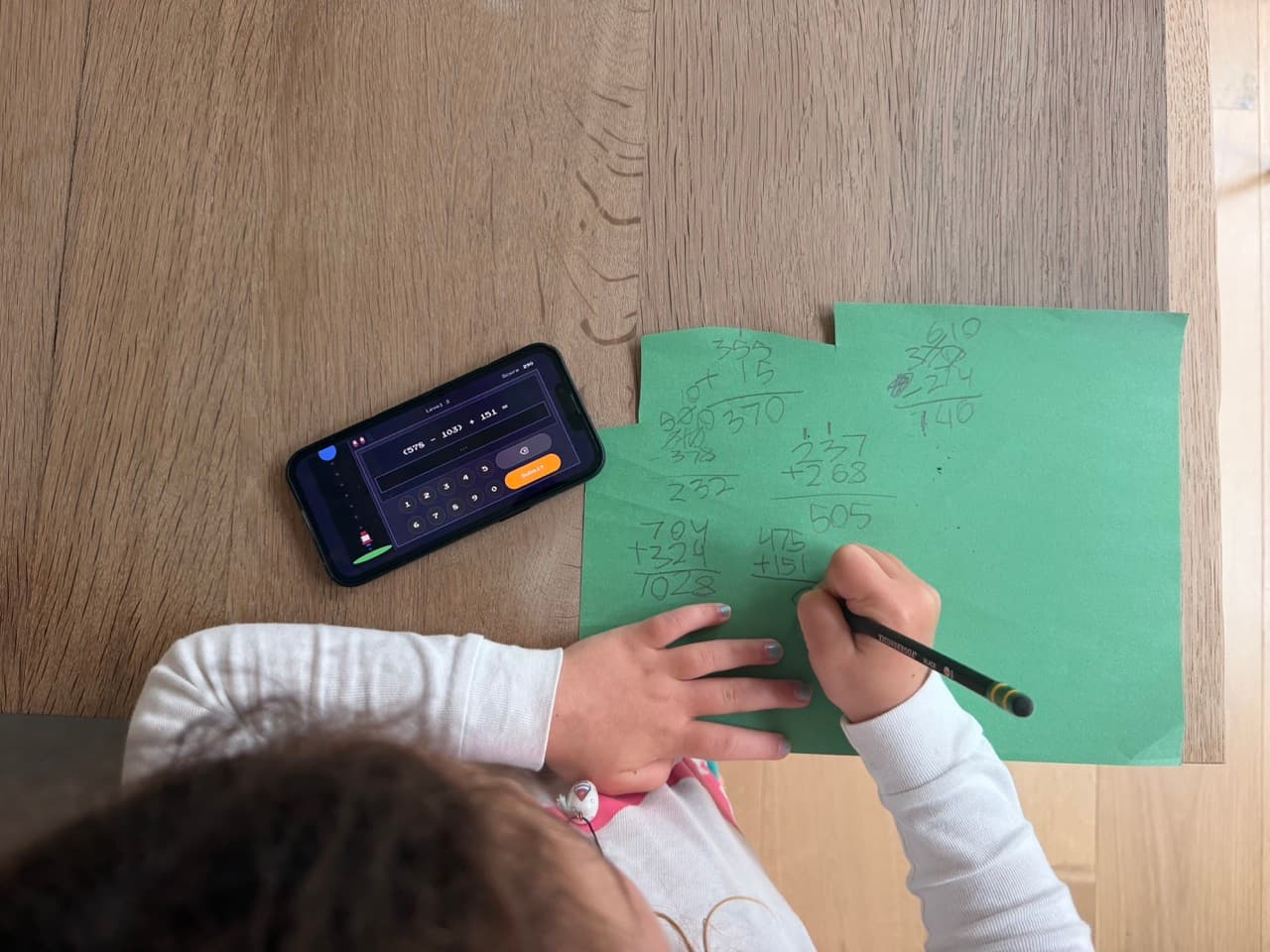 Child solving math equation on paper.